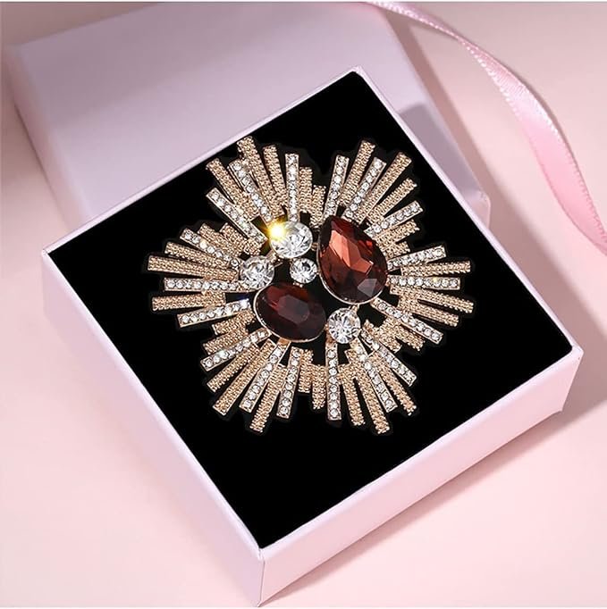 Broche vintage dorée en forme d’étoile avec strass et pierres rouges, présentée en écrin.