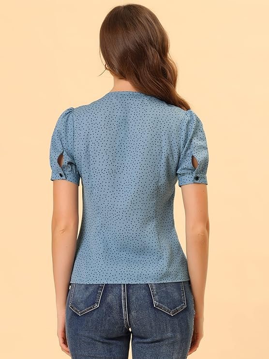 Femme portant un chemisier bleu à pois noirs avec col Claudine et manches courtes.