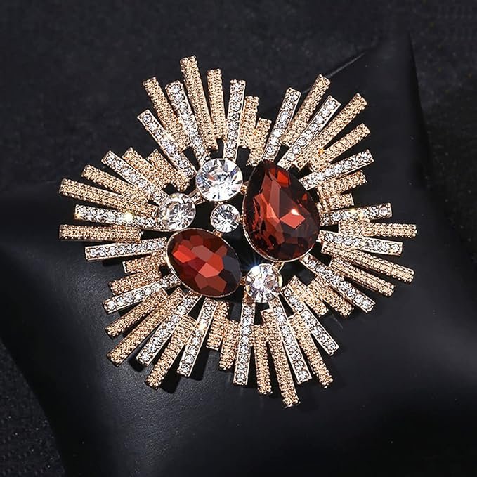 Broche vintage dorée en forme d’étoile avec strass et pierres rouges, présentée en écrin.