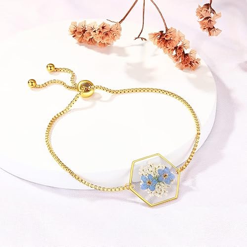 Bracelet doré avec pendentif hexagonal renfermant de vraies fleurs séchées bleues.
