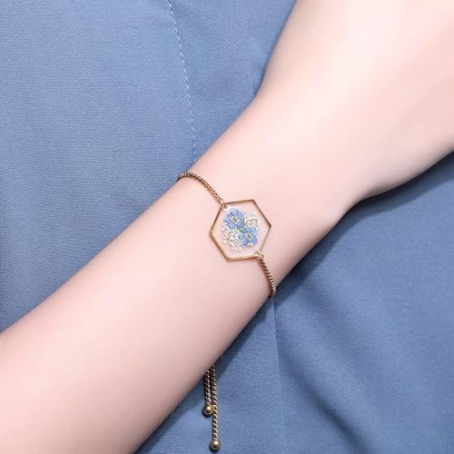 Bracelet doré avec pendentif hexagonal renfermant de vraies fleurs séchées bleues.
