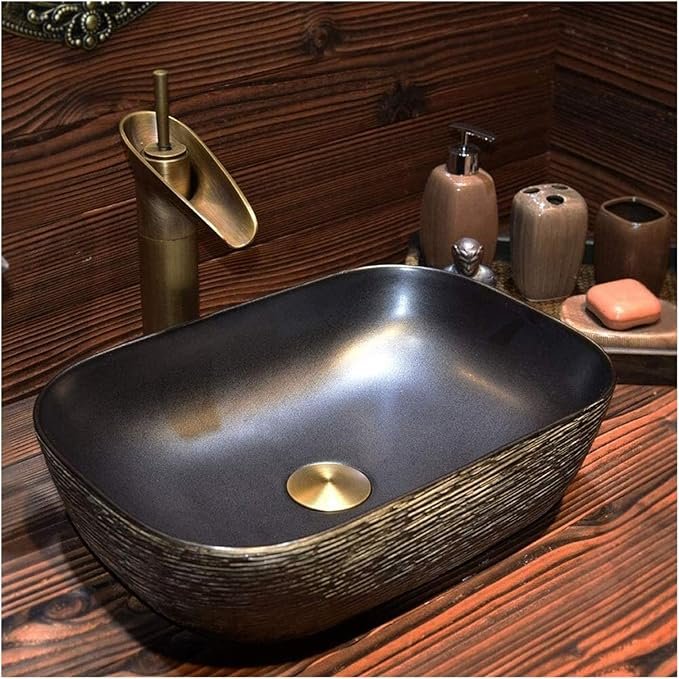 Vasque à poser vintage en céramique noire mate avec finition texturée effet bronze et robinet cascade doré brossé.